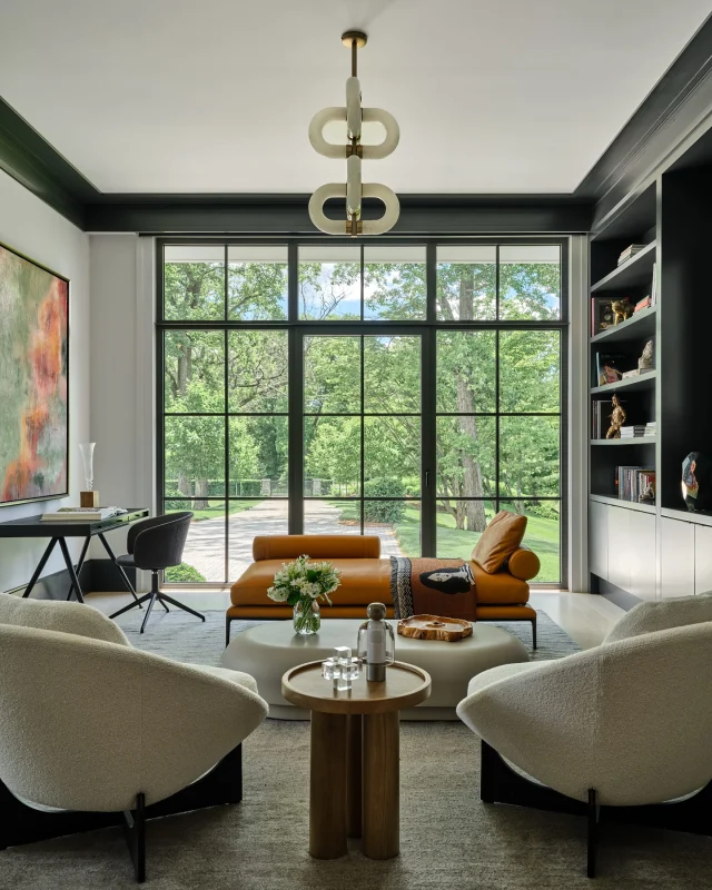 In this serene study, nature takes the lead. Floor-to-ceiling charcoal aluminum windows frame uninterrupted views of the patio and surrounding landscape, creating a quiet connection between indoors and out — a peaceful place to work, read, or simply pause.

Seen in @nehomemagazine 
Developer and Builder: @sbphomes 
Architecture: @apdarchitects 
Interior Design: @sbphomes @nimadesign 
Photography: @readmckendree
Floral design @greenofgreenwich
