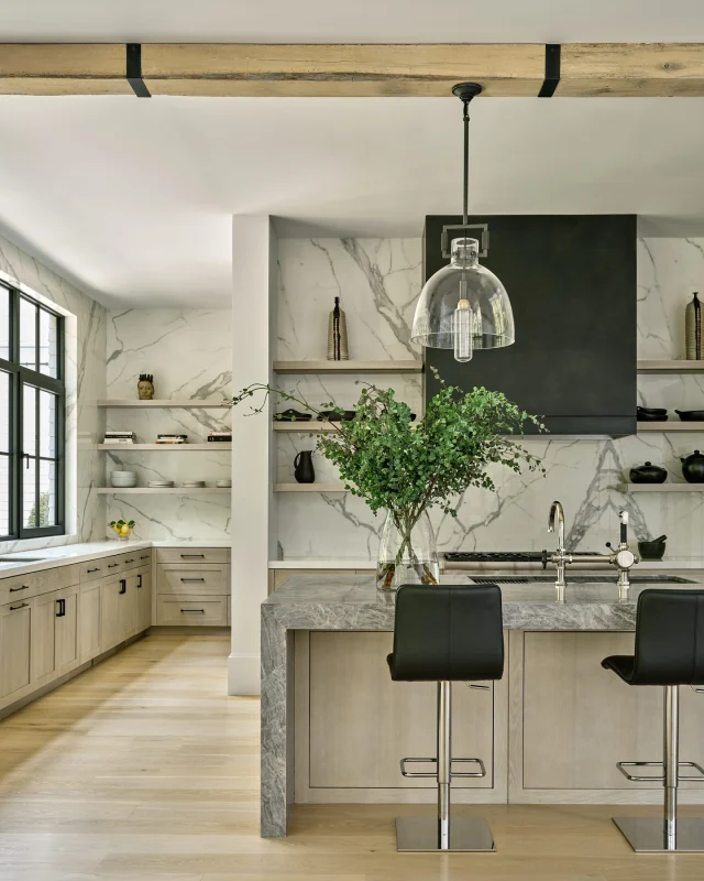A hidden gem behind the kitchen. 
A butler’s pantry is every entertainer’s secret weapon — offering ample storage and prep space that keeps the main kitchen looking effortlessly clean. 
This home features a bright, open prep kitchen in front, with a fully equipped pantry tucked behind to hide the hustle. 
Driftwood-stained white oak cabinetry brings quiet texture, while Thunder Bay quartzite wraps the island in soft drama. Nano-glass slabs mimic Calacatta marble from counter to ceiling, tying the space together with clean lines and tonal elegance.
Finished with Cantoni barstools and thoughtful details throughout — beauty meets utility, front to back.

Seen in @nehomemagazine 
Developer and Builder: @sbphomes 
Architecture: @apdarchitects 
Interior Design: @sbphomes @nimadesign 
Photography: @readmckendree
Floral design @greenofgreenwich