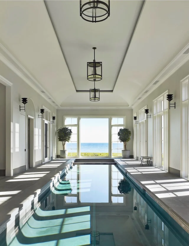 Rainy Memorial Day Weekends call for spaces like this.
From our coastal Connecticut project, as seen in @luxemagazine - an indoor retreat designed for slower mornings, long afternoons, and year-round comfort. Honed porcelain pavers surround the indoor lap pool, while custom lanterns and bronzed brass sconces bring warmth and atmosphere to the space on even the greyest days. 

Built by @sbphomes 
Architecture: @mitchell_studio 
Interior Design: @dkda 
Landscape Architecture: @hoblynandco 
Styling: @dorciakelley
Photography: @petermurdock_photo 

 #sbphomes #LuxeMagazine #IndoorOutdoorLiving #IndoorPool #CoastalConnecticut